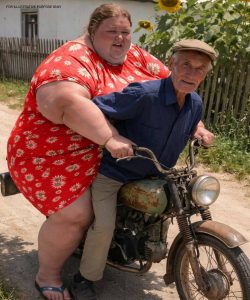 Everyone in the village was stunned when a 70-year-old man rode home on his old motorcycle with a woman forty years younger than him and introduced her as his wife 😨  But just a few days later, something happened that shocked the entire village all over again 😲😢  That day, a familiar but long-forgotten rattling sound echoed along the dusty road from the highway. People began peeking out from their gates, someone paused at the well, and Baba Nina even set down her bucket—she instantly recognized that old engine.  It was old Stepan.  He was already seventy. After his wife passed away, he barely spoke to anyone. He wore the same worn-out jacket every day and kept putting off even the simplest tasks. His roof leaked every spring, the fence leaned crookedly, and his garden had been overtaken by weeds.  But what shocked everyone most wasn’t that Stepan had suddenly started riding his old motorcycle again.  It was the woman sitting behind him.  She looked about thirty, wearing a blue dress with daisy prints, holding onto him as if it were completely natural. The motorcycle moved slowly, sputtering along, and at times they even had to push it with their feet, as if the engine had given up.  By the time they reached Stepan’s yard, neighbors had already gathered along the fences.  “Oh my God… he’s gone crazy,” Baba Nina whispered.  “Is that his granddaughter?” Grandpa Kolya asked.  But Stepan acted as if he heard nothing. He took off his helmet, helped the woman down, and said calmly:  “Everyone, meet Lena. My wife.”  For a few seconds, the entire street fell silent—even the chickens stopped clucking. Then the whispers began.  Some people laughed. Others shook their heads. A few openly said that after losing his wife, the old man had completely lost his mind.  “She’s forty years younger than him!”  “She must be after his money.”  “Let’s see how long she lasts here.”  Lena heard every word. But she simply smiled gently and greeted everyone, as if nothing unusual was happening.  And yet, just a few days later, the entire village would be shocked again—when they saw what was really happening inside the old man’s house, and what his new wife was doing 😨